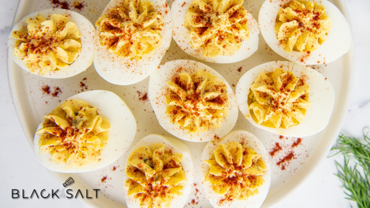 Deviled Eggs, hard-boiled eggs halved and filled with a creamy and seasoned yolk mixture, garnished with various toppings, creating a classic and flavorful appetizer option.